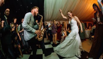 Wedding saxophone player from DJ and Sax duo dances with bride.