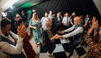 Two wedding guests dance hand in hand to wedding DJ