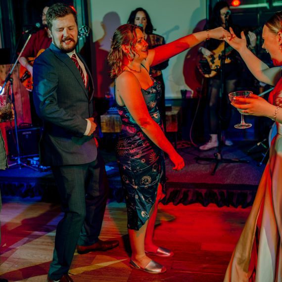 A Yorkshire wedding band performs lively music on stage, featuring a female vocalist and guitarist, and a drummer in the background.