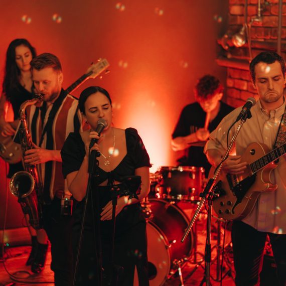 The Cat and Mac Band, a live wedding band in Yorkshire, engaged in an energetic evening performance with vibrant stage lighting.