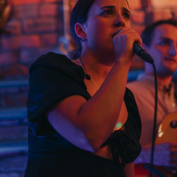 Emotional performance by the vocalist of a Yorkshire wedding band with bandmates in the background at a lively wedding reception.